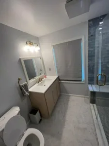 Vanity area with modern sink, mirror, and toilet in a recently completed Full Bathroom Renovation.