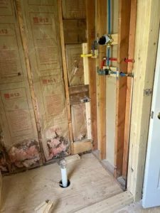 Exposed insulation and plumbing lines during the early stages of a Full Bathroom Renovation.
