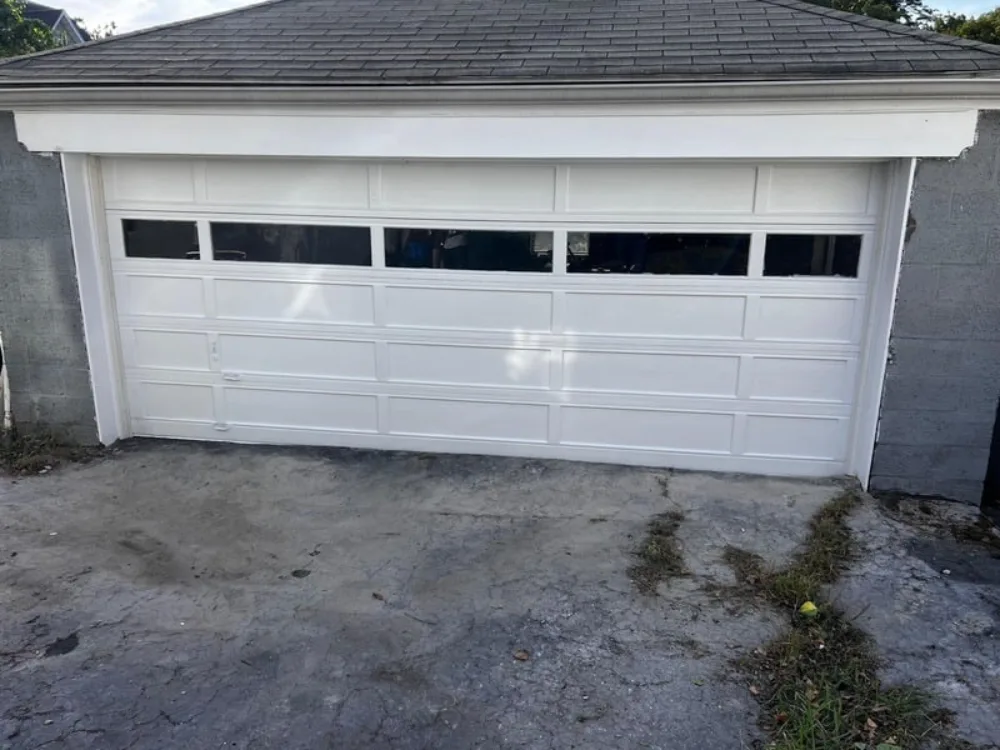 Exterior view of the completed garage restoration project with a white garage door.