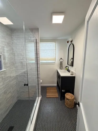 Wide view of the completed custom bathroom renovation, showcasing the vanity, mirror, toilet, and shower.